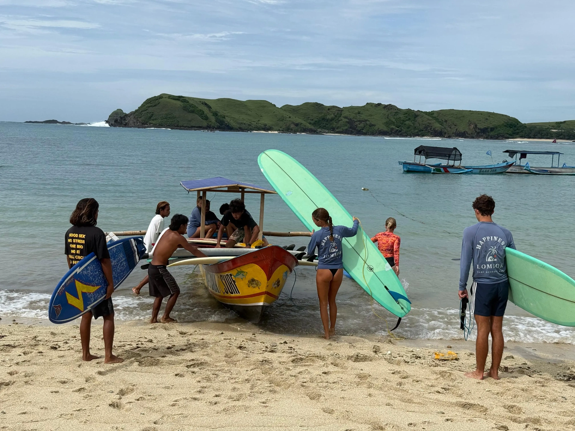 Surf students with boards preparing for boat ride to surf break at Gerupuk Bay Lombok